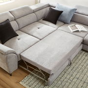 Ecksofa MAROLA in hellgrauem Stoff mit ausziehbarer Liegefläche, zwei schwarzen und einem blauen Kissen, aus der Vogelperspektive fotografiert.