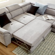 Ecksofa MAROLA in hellgrauem Stoff mit ausziehbarer Liegefläche, zwei schwarzen und einem blauen Kissen, aus der Vogelperspektive fotografiert.