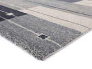 Nahaufnahme eines modernen Frisé-Teppichs mit geometrischem Muster in Grautönen, seitliche Perspektive.