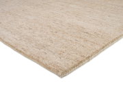 Nahaufnahme eines Wollteppichs in Beige mit melierter Struktur, von der Seite fotografiert.