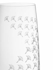 Nahaufnahme eines Longdrinkglases mit elegantem, weiß mattem Muster und filigranen Verzierungen, seitliche Perspektive