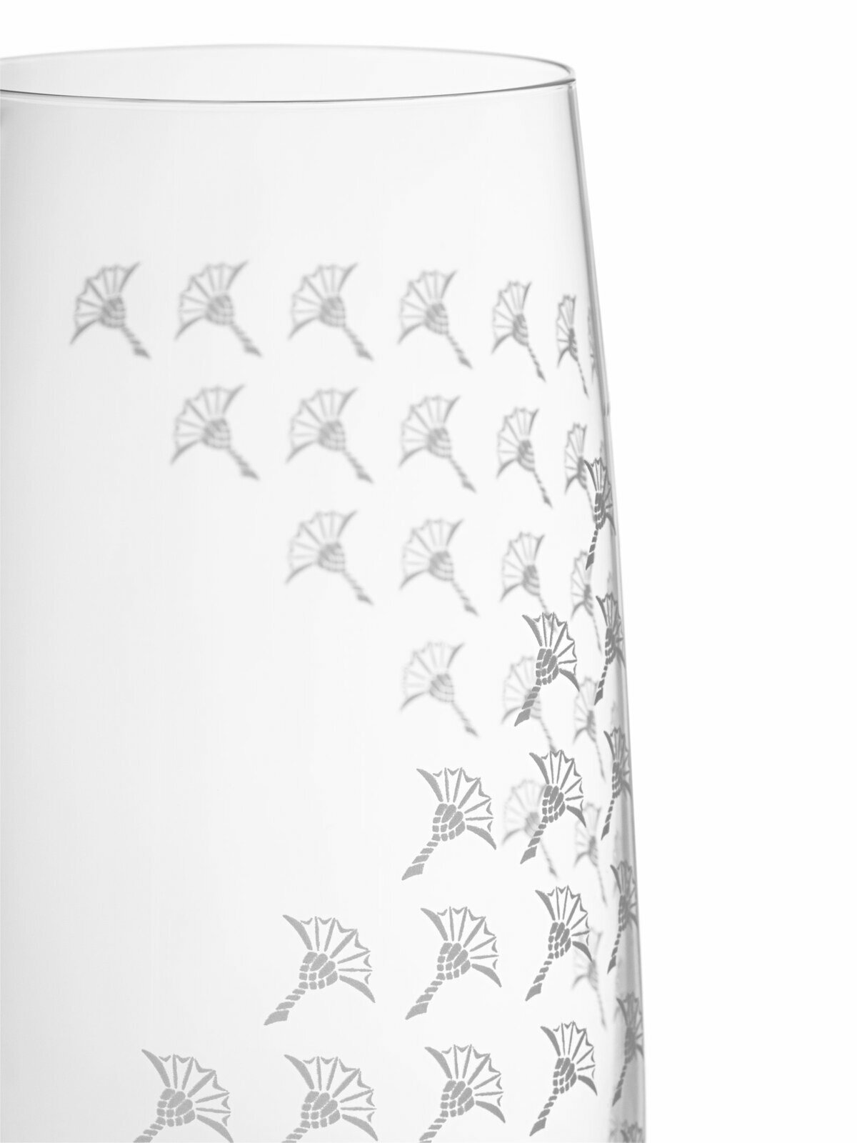 Nahaufnahme eines Longdrinkglases mit elegantem, weiß mattem Muster und filigranen Verzierungen, seitliche Perspektive