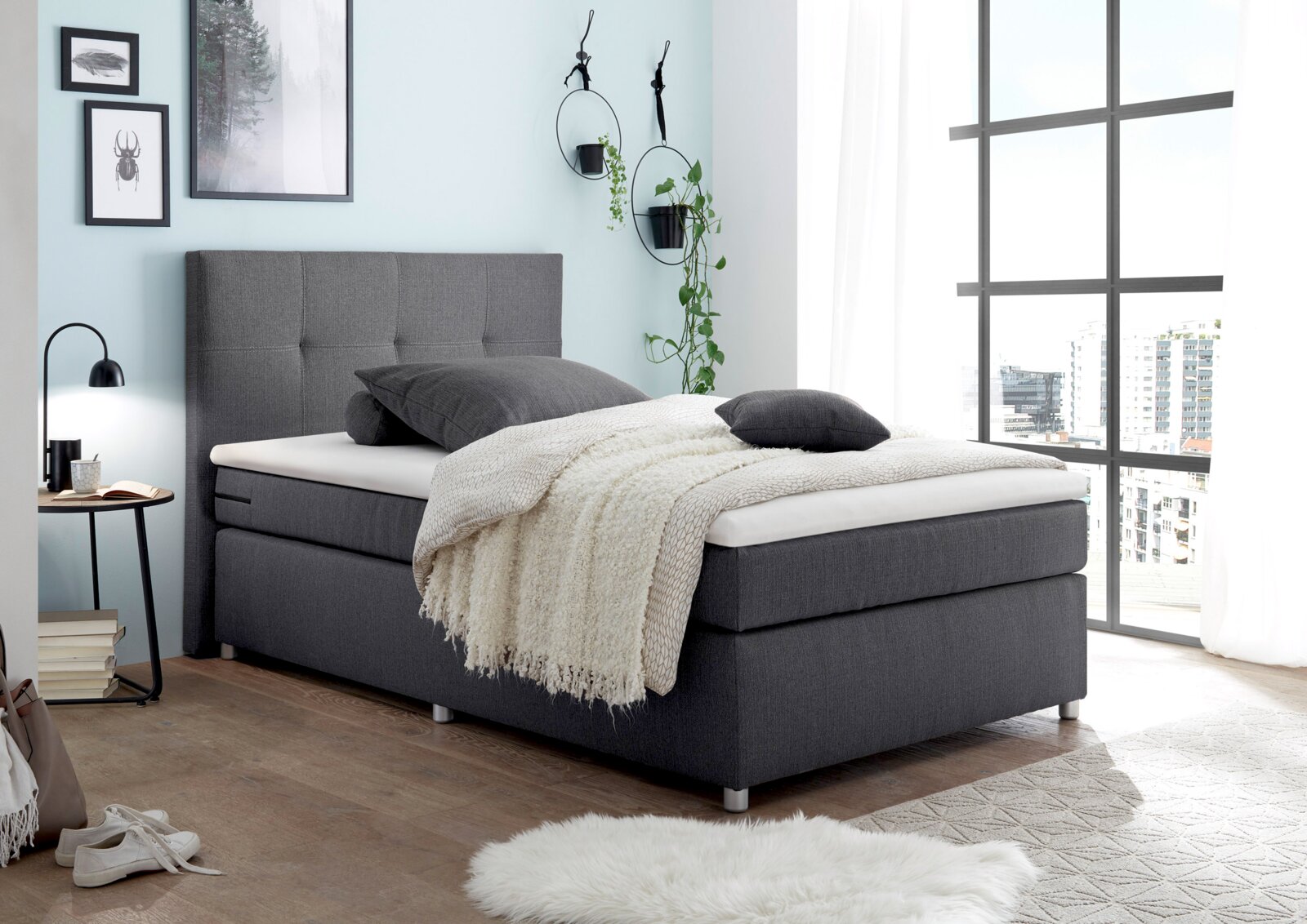 Modernes Boxspringbett in einem hellen Schlafzimmer, seitliche Perspektive