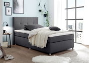 Modernes Boxspringbett in einem hellen Schlafzimmer, seitliche Perspektive