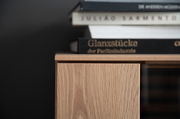 Nahaufnahme eines Highboards aus Holz mit Büchern darauf, seitliche Perspektive