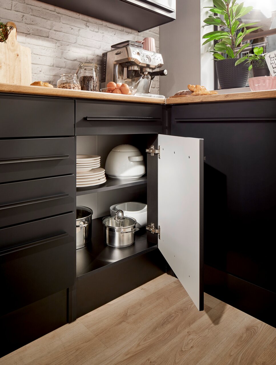 Eckunterschrank in einer modernen Küche, geöffnet, mit Töpfen und Geschirr, aus der Perspektive von vorne rechts fotografiert.