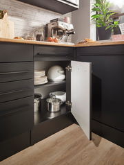 Eckunterschrank in einer modernen Küche, geöffnet, mit Töpfen und Geschirr, aus der Perspektive von vorne rechts fotografiert.