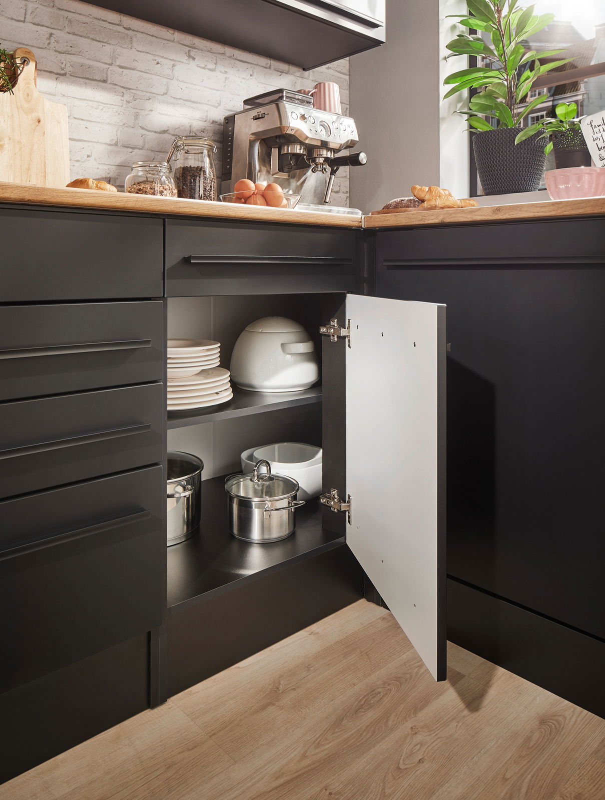 Eckunterschrank in einer modernen Küche, geöffnet, mit Töpfen und Geschirr, aus der Perspektive von vorne rechts fotografiert.