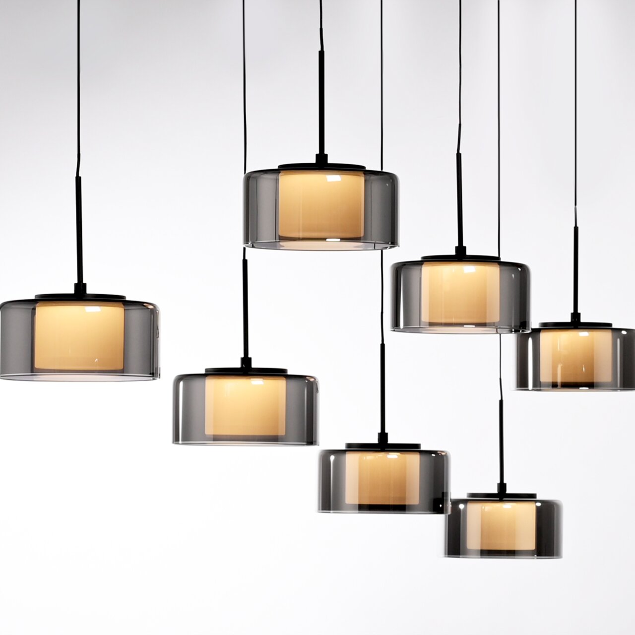 Moderne Pendelleuchte RIKA mit mehreren zylindrischen, rauchgrauen Glasschirmen, die von der Decke hängen. Seitenansicht.