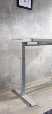 Seitliche Ansicht eines höhenverstellbaren E-Schreibtischs mit modernem Design und Metallgestell vor einer Betonwand.