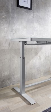 Seitliche Ansicht eines höhenverstellbaren E-Schreibtischs mit modernem Design und Metallgestell vor einer Betonwand.