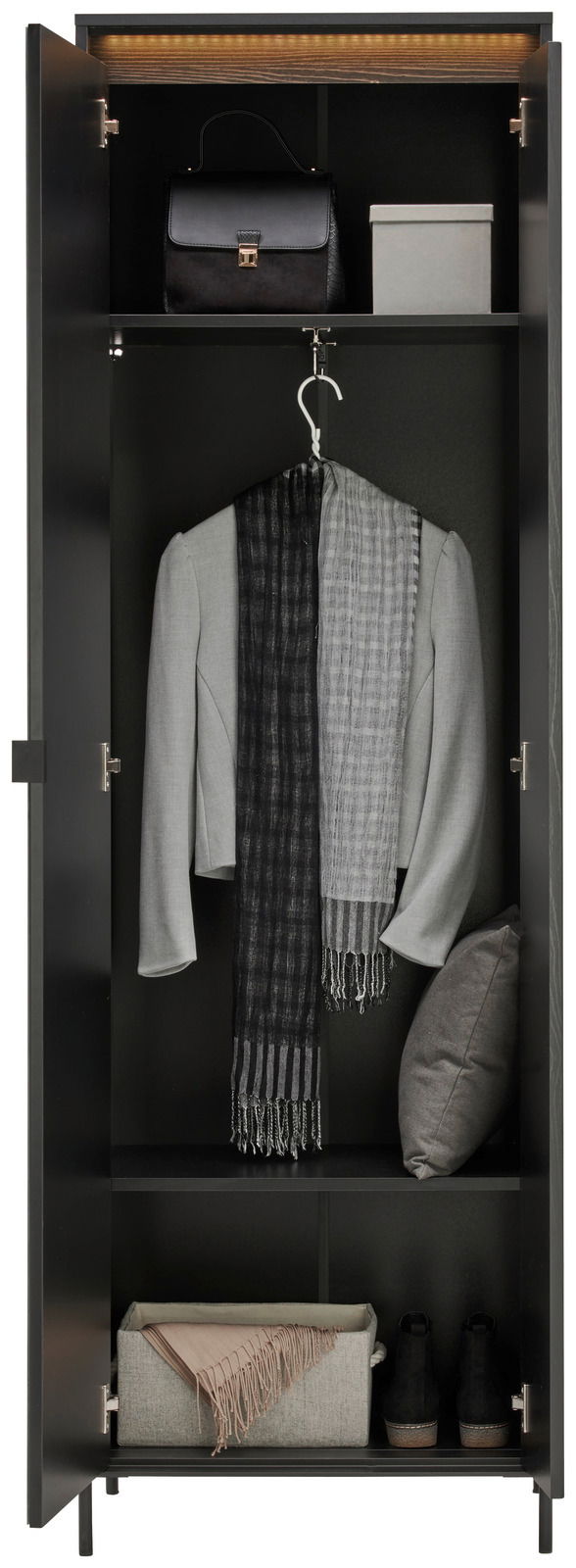 Garderobenschrank in schwarzer Farbe, frontal geöffnet, mit mehreren Fächern. Oben eine Handtasche und eine Box, in der Mitte ein grauer Blazer mit Schal, unten ein Kissen und ein Paar Schuhe.