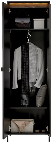 Garderobenschrank in schwarzer Farbe, frontal geöffnet, mit mehreren Fächern. Oben eine Handtasche und eine Box, in der Mitte ein grauer Blazer mit Schal, unten ein Kissen und ein Paar Schuhe.