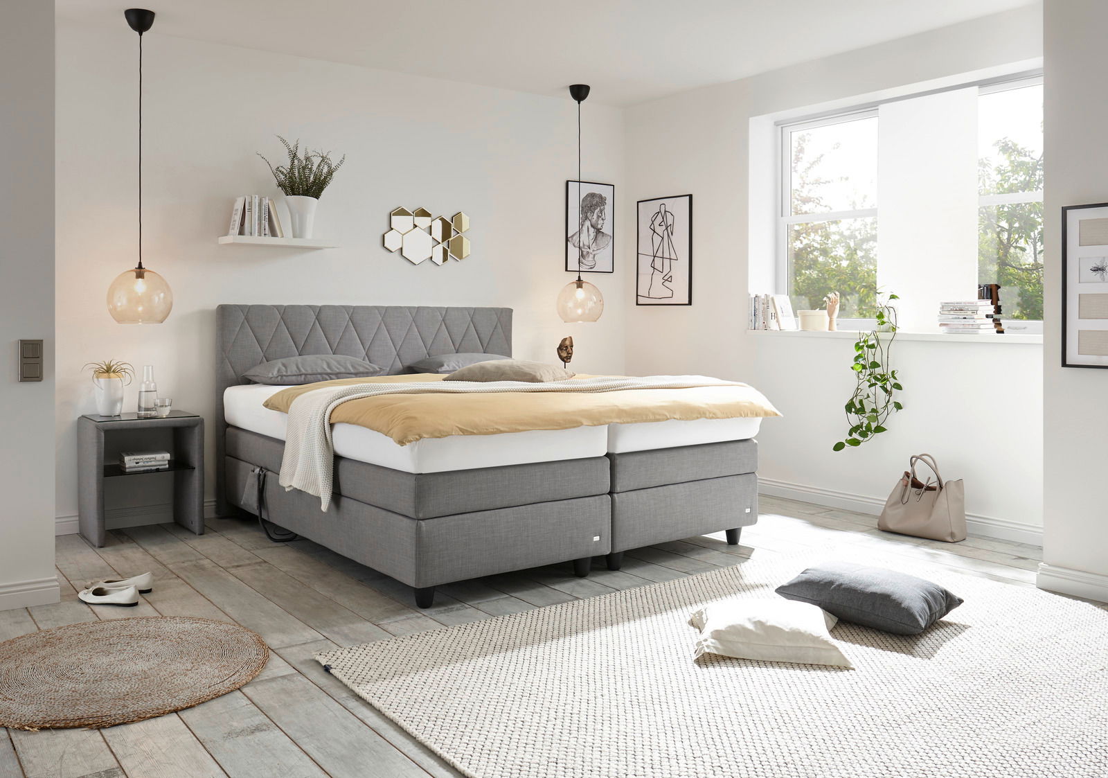 Modernes Boxspringbett in einem hellen Schlafzimmer, seitliche Perspektive, mit grauem Kopfteil und eleganter Dekoration.