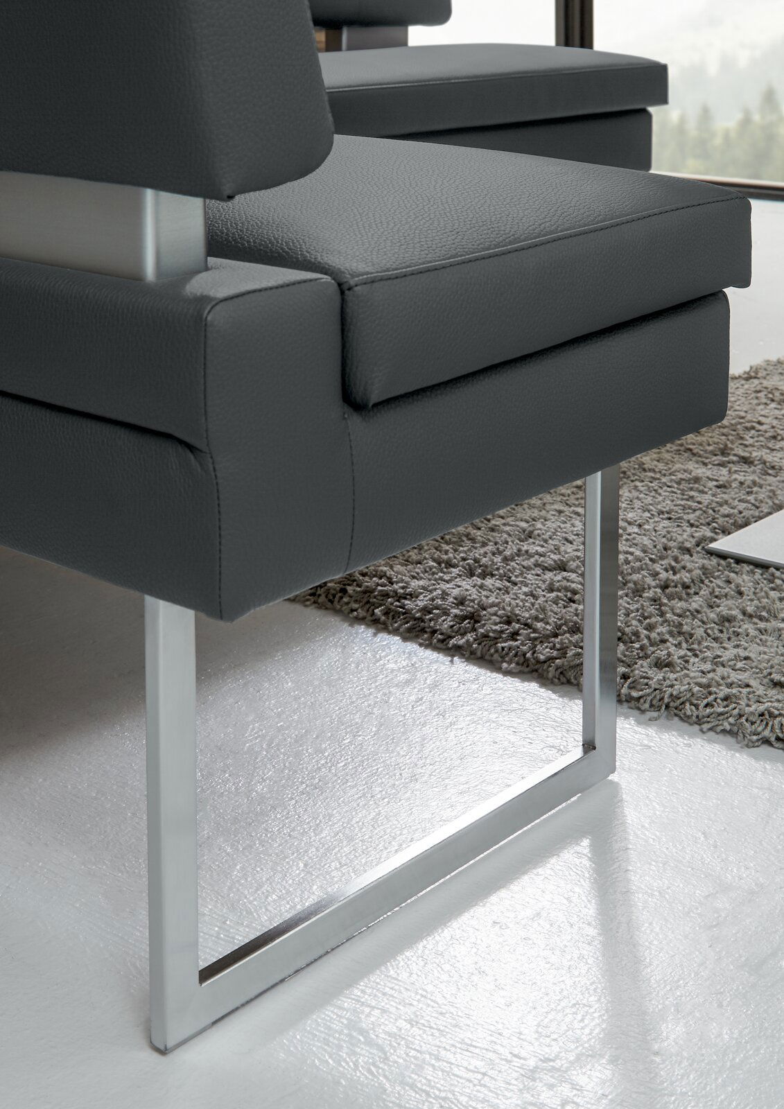 Detailansicht einer modernen Eckbank mit grauem Polster und Metallgestell.