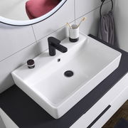 Moderner Waschtisch mit schwarzem Wasserhahn, Zahnputzbecher und Handtuch, aus der Vogelperspektive.