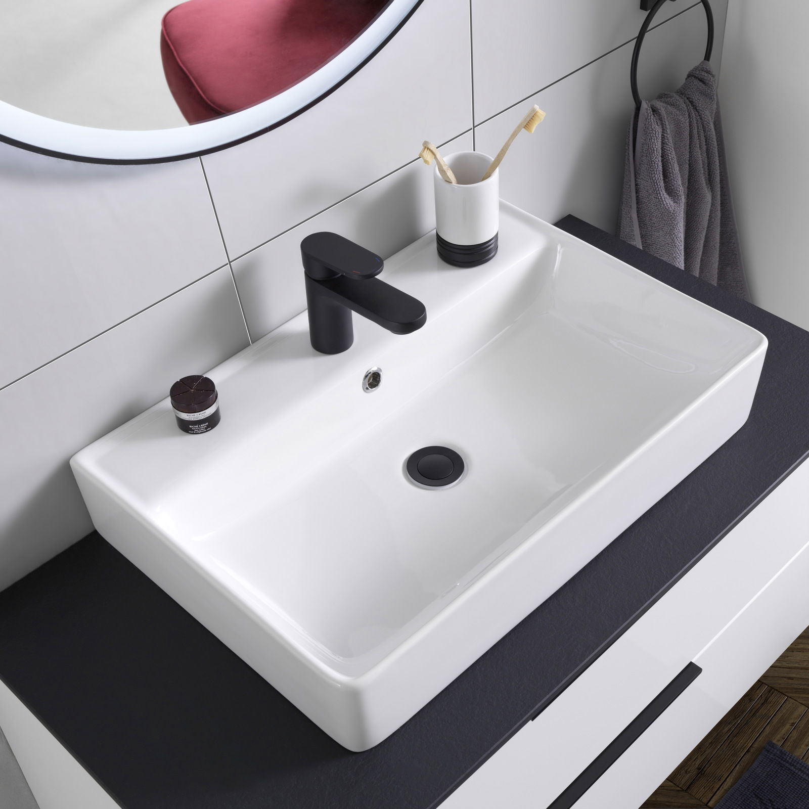 Moderner Waschtisch mit schwarzem Wasserhahn, Zahnputzbecher und Handtuch, aus der Vogelperspektive.