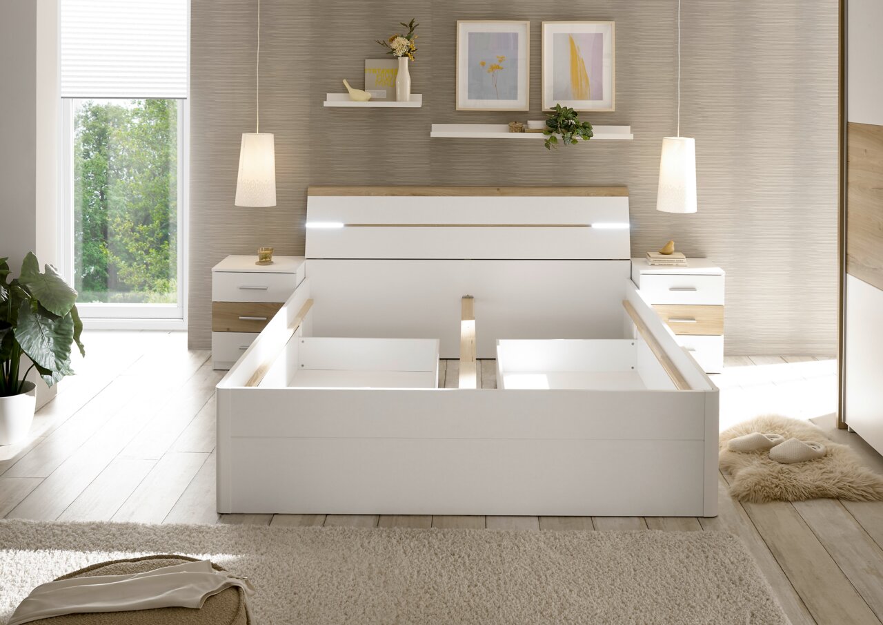 Modernes Schlafzimmer mit weißem Bettgestell in Frontalansicht, flankiert von zwei Nachttischen und dekorativen Elementen.