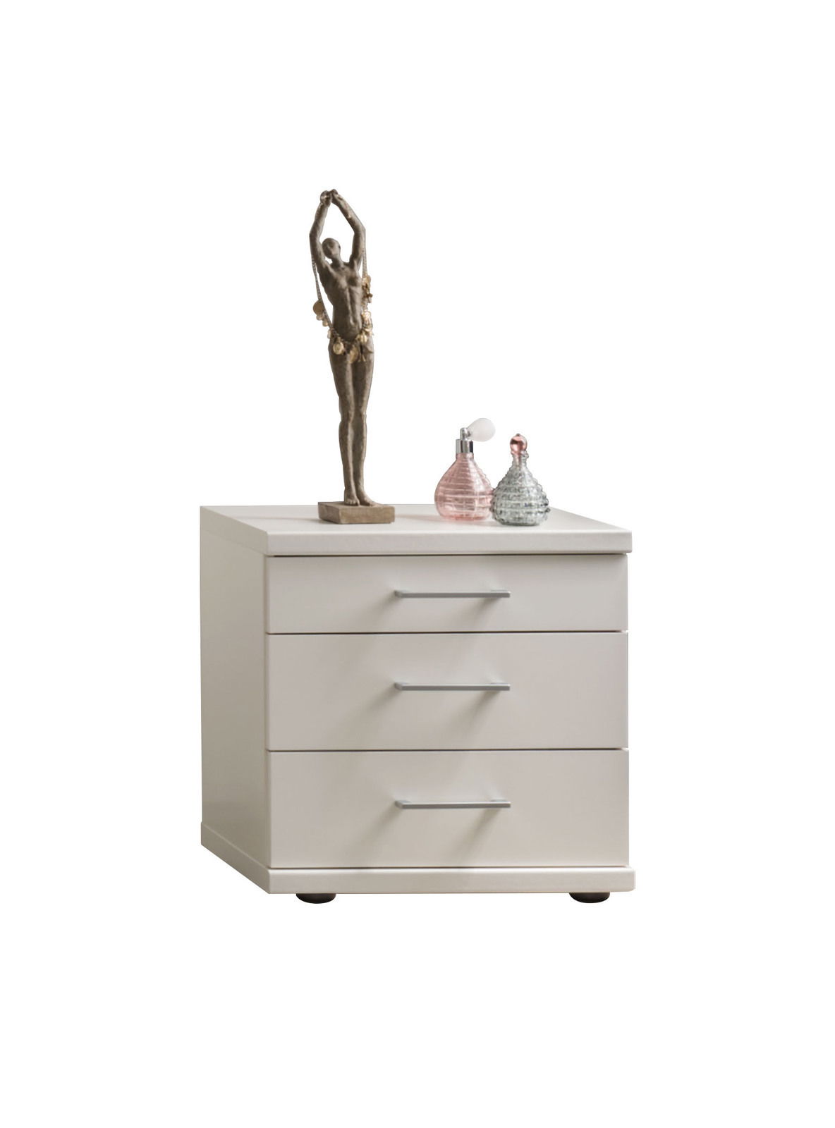 Weiße Nachtkonsole mit drei Schubladen, dekoriert mit einer Skulptur und zwei Parfümflaschen, frontal betrachtet.