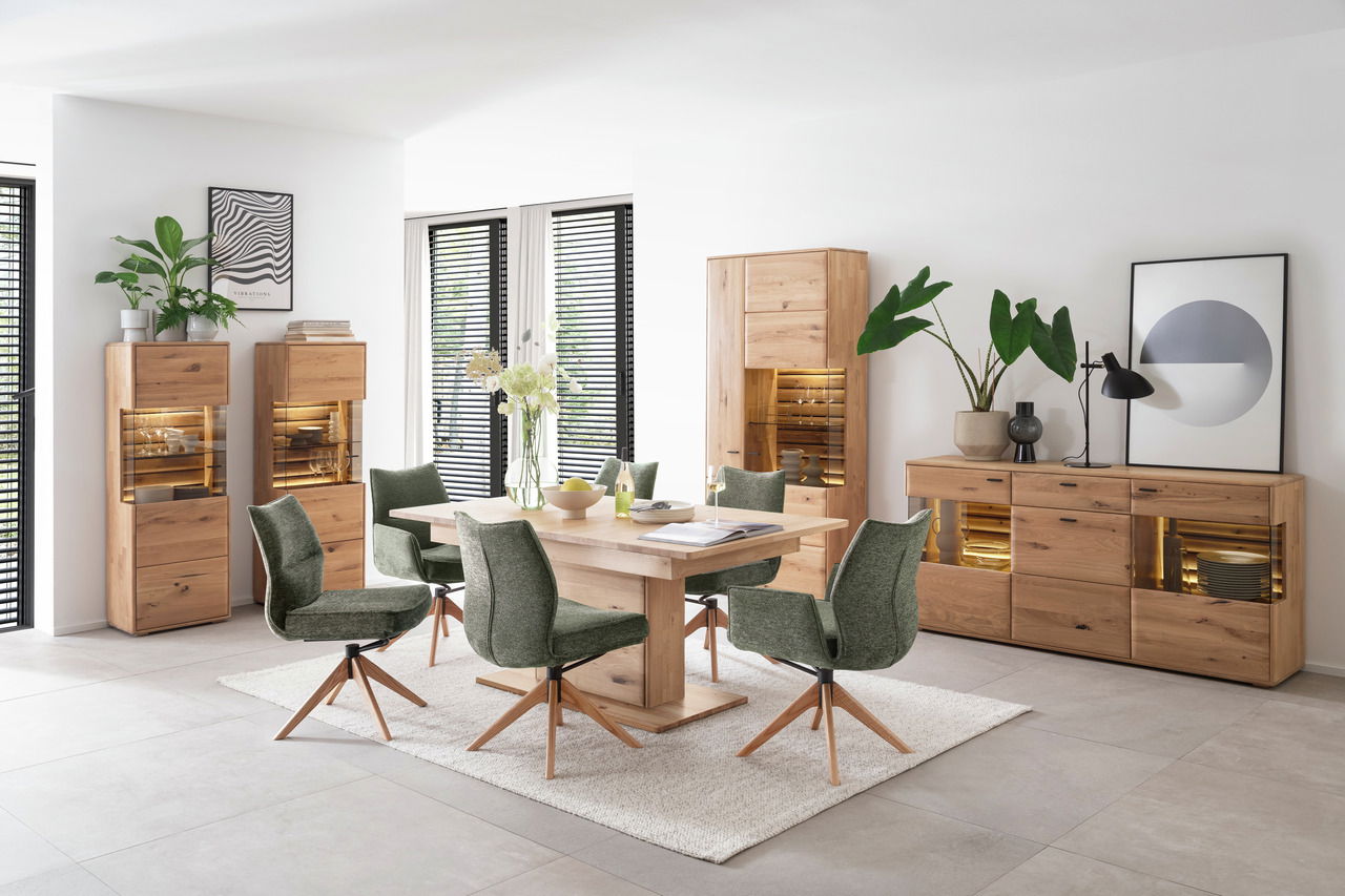Moderne Esszimmerkombination mit Holztisch, grünen Stühlen und beleuchteten Vitrinen aus Holz, seitliche Perspektive.
