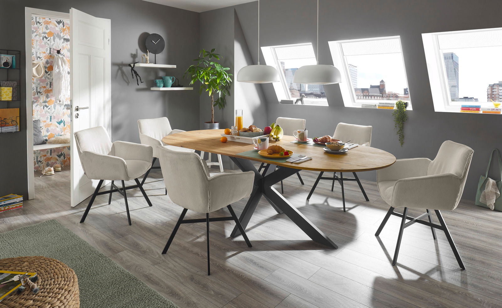 Set one by Musterring Esstisch SET ONE LAKEWOOD Moderner Esstisch mit ovaler Holzplatte und schwarzen Metallbeinen, umgeben von sechs beigen Stühlen in einem hellen Esszimmer mit Dachfenstern, seitliche Perspektive.