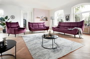 Wohnzimmer mit moderner Polstergarnitur in Lila, bestehend aus einem 3er-Sofa, einem 2er-Sofa und einem Sessel, aus der Perspektive von vorne betrachtet.