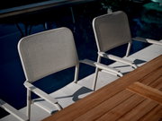 Zwei graue Stapelsessel aus Metall neben einem Pool, seitliche Perspektive