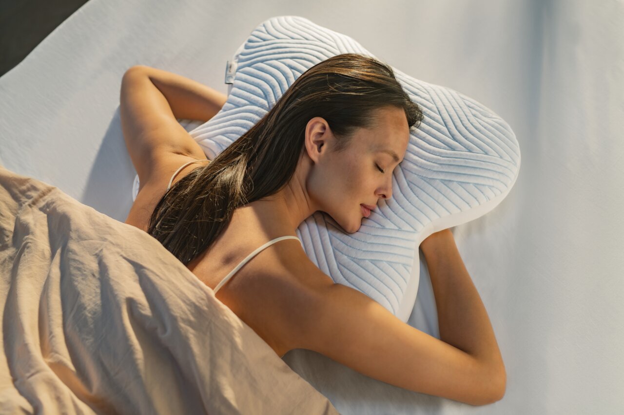 Tempur Schlafkissen ALL AROUND Frau schläft auf einem ergonomischen Schlafkissen in Schmetterlingsform, Seitenansicht