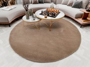 Runder, beiger Teppich Soft Dream mit einem Durchmesser von ca. 150 cm, platziert in einem modernen Wohnzimmer mit einem eleganten Couchtisch und einem Schachbrett, aus der Vogelperspektive betrachtet.
