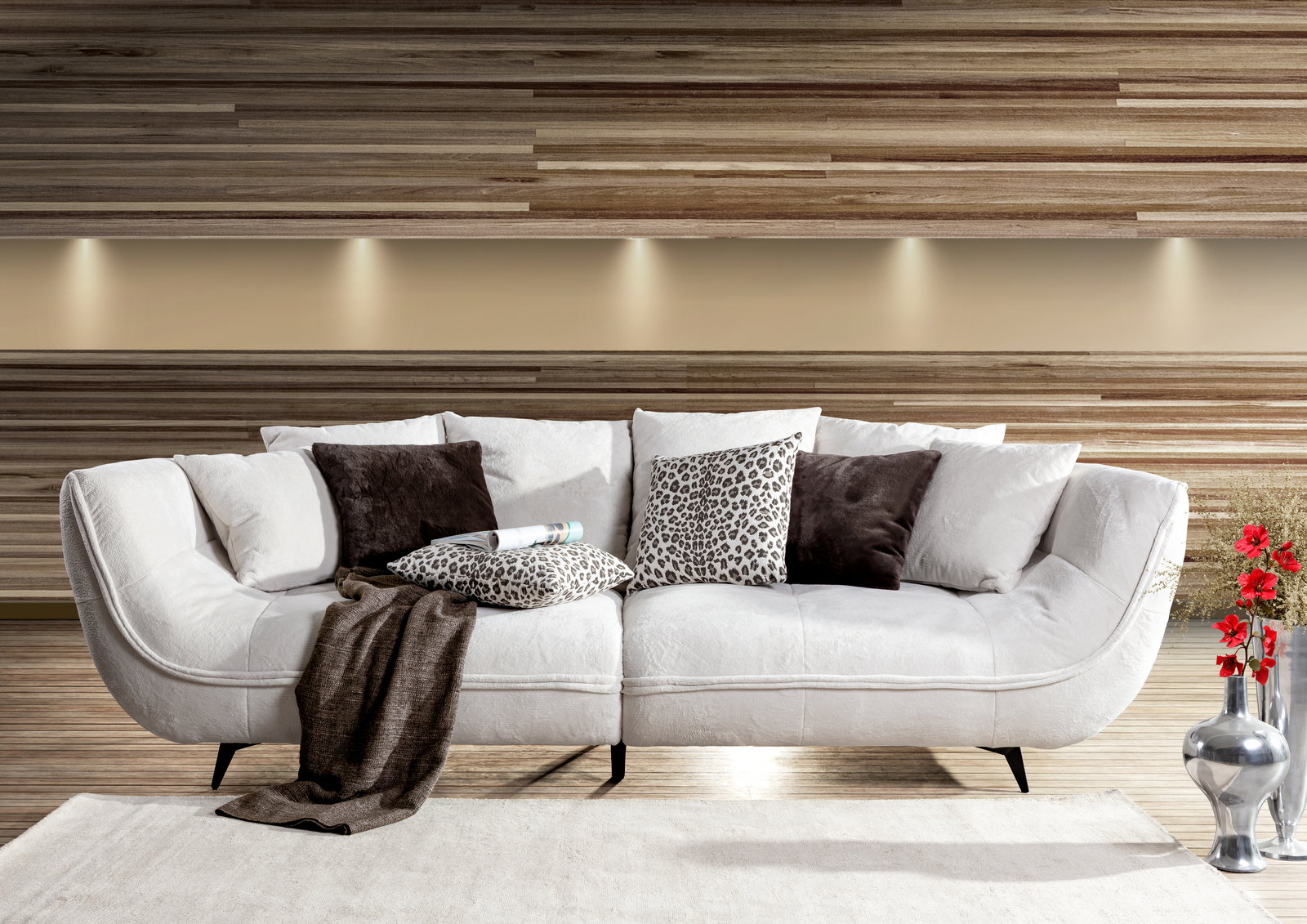 Elegantes Megasofa in Weiß mit dekorativen Kissen in Leopardenmuster und Braun, frontal fotografiert vor einer modernen Holzwand.