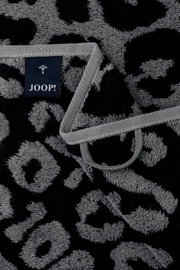 Nahaufnahme eines grauen Gästetuchs mit schwarzem Leopardenmuster und einem Joop-Label.
