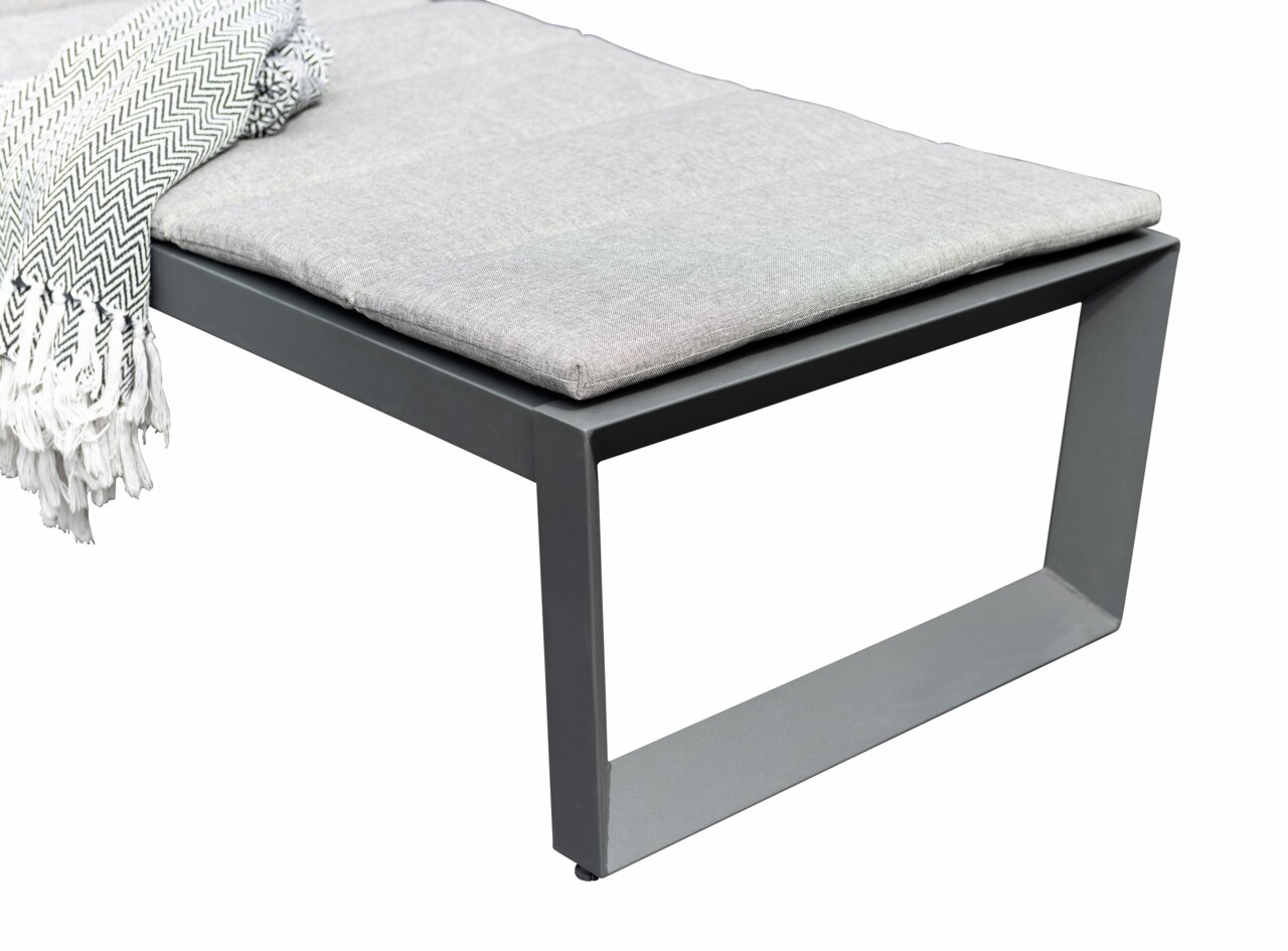 Detailfoto van een moderne ligstoel met een grijs metalen frame en een gestoffeerde zitting, gezien vanaf de zijkant.