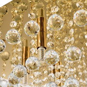 Close-up van een luxe plafondlamp met gouden elementen en schitterende kristallen hangers, gezien van onderaf.