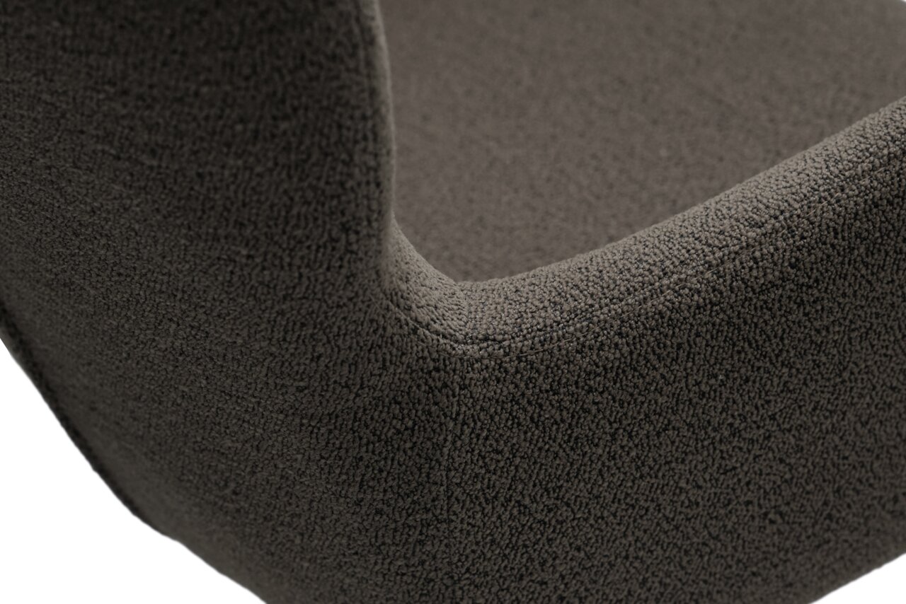 Close-up van een fauteuil met een donkergrijze, gestructureerde stoffen bekleding, gezien vanuit de zijkant