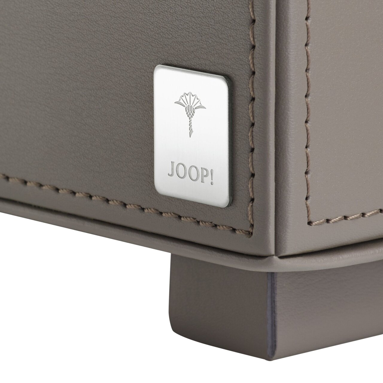 Close-up van een grijs dienblad met het Joop-logo op een metalen inlegstuk, vanuit een zijdelingse hoek gefotografeerd.