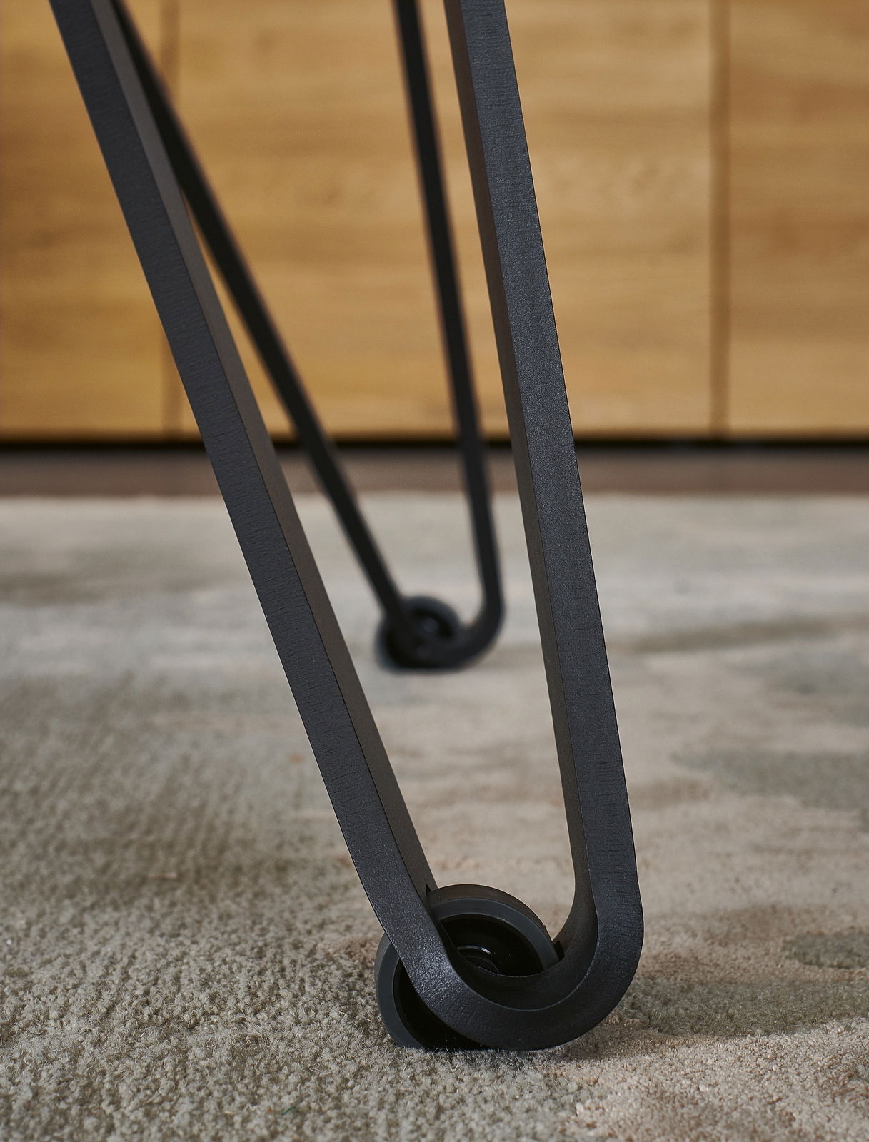 Nahaufnahme eines Tischbeins mit modernem Design und Rollen, Perspektive von unten.