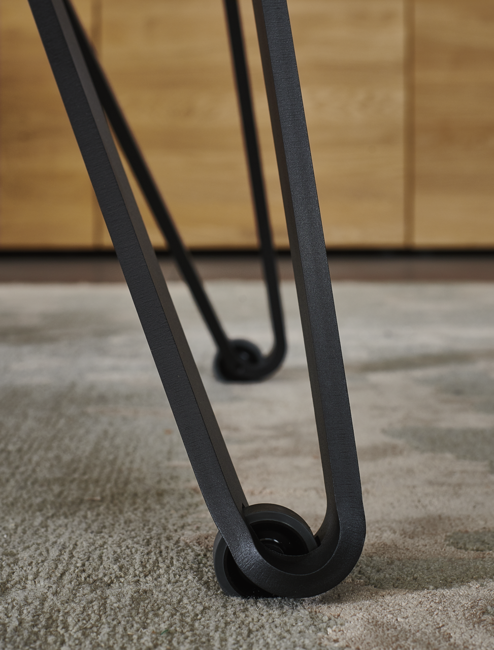 Nahaufnahme eines Tischbeins mit modernem Design und Rollen, Perspektive von unten.