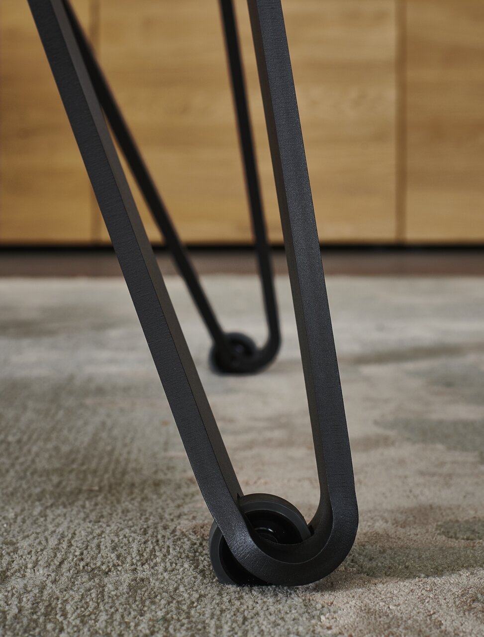 Nahaufnahme eines Tischbeins mit modernem Design und Rollen, Perspektive von unten.