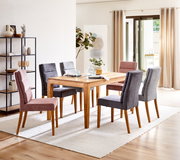 Esszimmer mit einem Holztisch und sechs gepolsterten Stühlen in Grau und Rosa, seitliche Perspektive