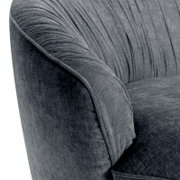 Nahaufnahme eines grauen, runden Megasofas mit weicher Polsterung und eleganten Falten im Stoff, seitliche Perspektive.