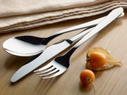 Elegantes Besteck-Set bestehend aus Löffel, Messer und Gabel in Nahaufnahme auf einem Holztisch, begleitet von Physalis-Früchten und einem beigen Stofftuch.