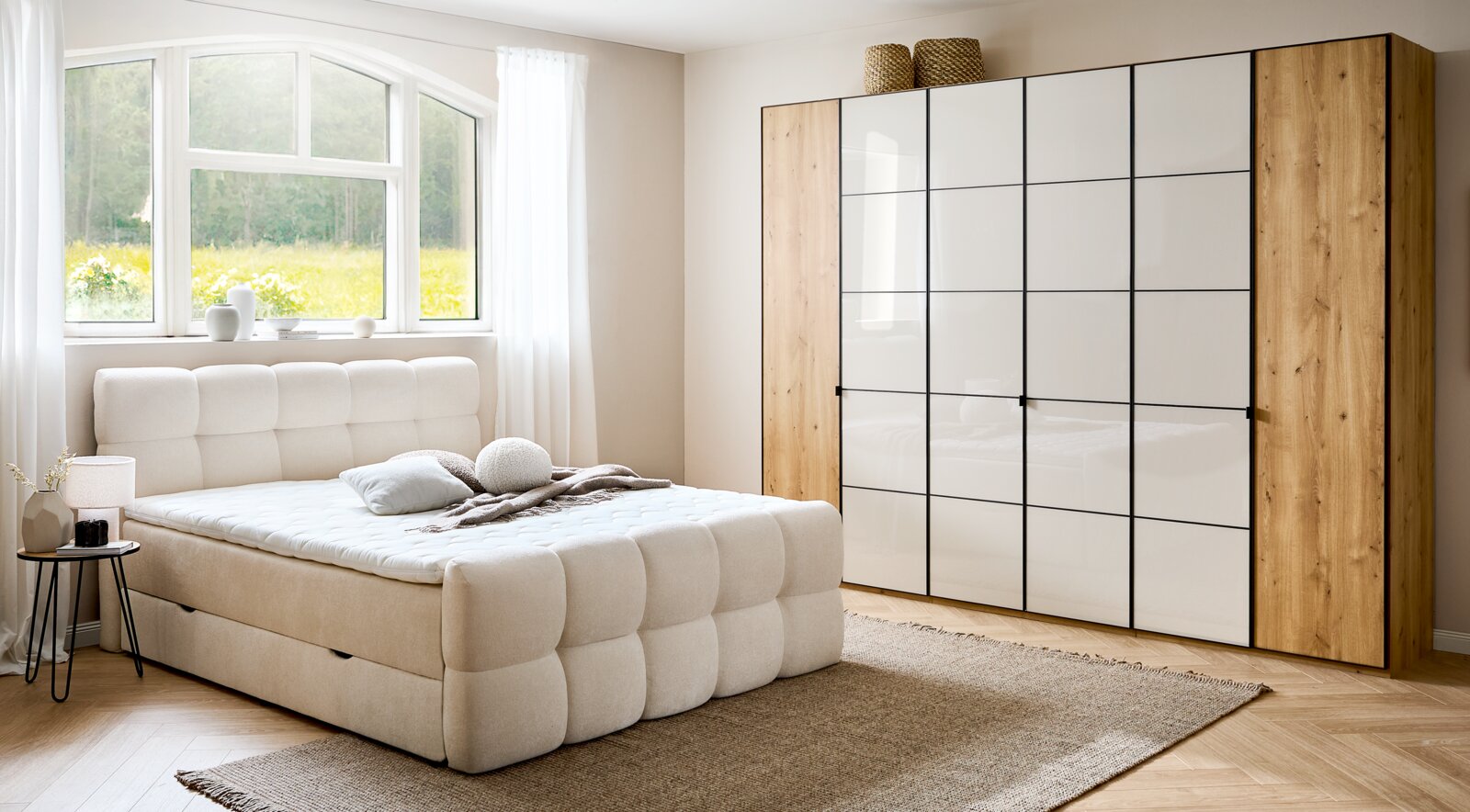 Modernes Boxbett in einem hellen Schlafzimmer mit großem Fenster, beige gepolstertem Kopfteil und passendem Teppich, seitliche Perspektive.