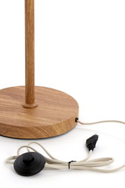Runder Holzsockel einer Stehlampe mit Holzstange, Textilkabel, Fußschalter und Eurostecker auf weißem Hintergrund, Nahaufnahme aus leicht seitlicher Perspektive