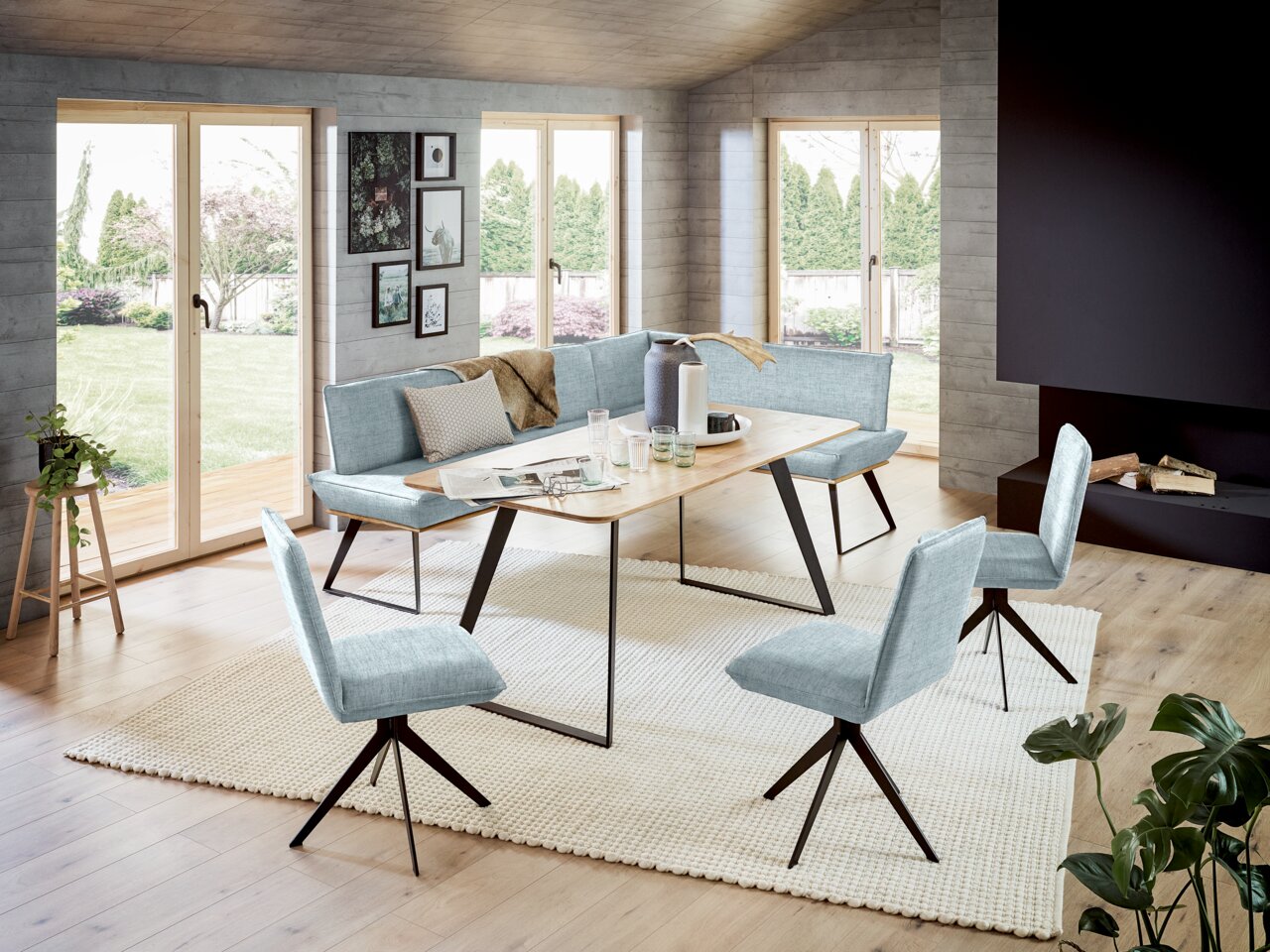 Voleo Eckbank 163x203 cm MALIBU Moderne Eckbank 163x203 cm in einem hellen Raum mit großen Fenstern, umgeben von stilvollen Stühlen und einem Holztisch, aus der Perspektive des Wohnzimmers betrachtet.