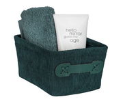 Dunkelgrüner Badkorb Anela mini, gefüllt mit einem Handtuch und einer Tube, aus schräger Perspektive fotografiert.