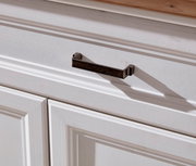 Nahaufnahme eines weißen Schranks mit einer dunklen Metallgriffleiste, von schräg oben fotografiert.