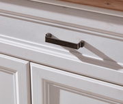 Nahaufnahme eines weißen Schranks mit einer dunklen Metallgriffleiste, von schräg oben fotografiert.