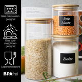 Drei Vorratsgläser mit Holzdeckeln, gefüllt mit roten Linsen, Reis und Zucker, auf einer Küchenarbeitsplatte. Seitliche Ansicht.