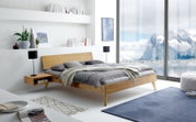 Modernes Bettgestell aus Holz in einem hellen, minimalistischen Schlafzimmer mit Blick auf eine verschneite Berglandschaft durch große Fenster. Perspektive von der Seite.