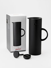 Schwarze Isolierkanne mit abgerundeter Form und Griff, abgebildet aus einer leicht seitlichen Perspektive neben ihrer Verpackung.